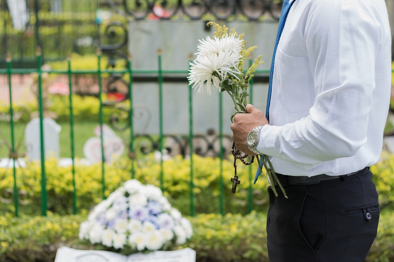 image of a man standing over a memorial with white flowers in his hand