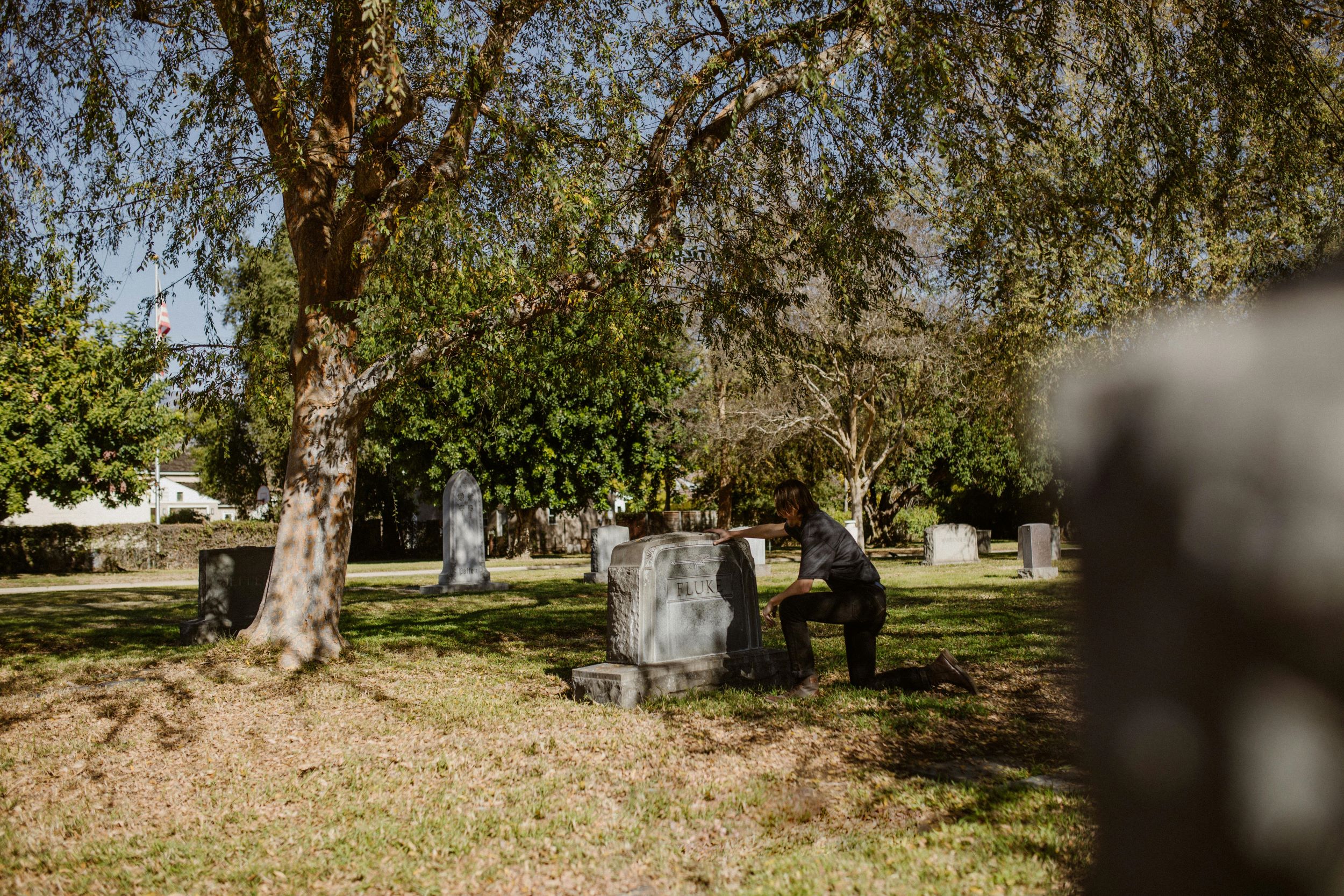 image of a woman crouching down at a headstone